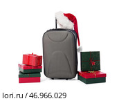 Чемодан в шляпе Санты и различных подарочных коробках на белом фоне. Концепция рождественских каникул. Стоковое фото, фотограф Pixel_shot / Фотобанк Лори