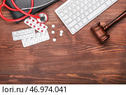Молоток судьи, таблетки, клавиатура ПК и стетоскоп на деревянном фоне. Концепция реформы здравоохранения. Стоковое фото, фотограф Pixel_shot / Фотобанк Лори