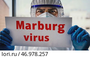Doctor holding a banner with text Marburg Virus sign. Scientist in protective gear, gloves and medical mask. New epidemic illness. Outbreak of infectious disease spreading, worldwide pandemic. Стоковое AI-видео, аниматор Марина Демидюк / Фотобанк Лори