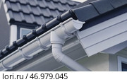Contemporary Gutter Installed on a Residential House Roof to Enhance Functionality. Clean well maintained rain gutter system. Roof architecture effectively. Polymer storm drainage. Home architectural. Стоковое AI-видео, аниматор Марина Демидюк / Фотобанк Лори