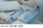 Scrub nurse hands in rubber gloves cutting sterile gauze. Стоковое фото, фотограф David Kashakhi / Фотобанк Лори