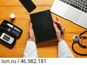 Женщина-врач с блокнотом, цифровым глюкометром и ручкой на деревянном фоне. Стоковое фото, фотограф Pixel_shot / Фотобанк Лори