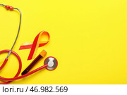 Лента осведомленности с образцом крови и стетоскопом на желтом фоне. Концепция гепатита. Стоковое фото, фотограф Pixel_shot / Фотобанк Лори