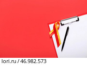 Лента осведомленности с буфером обмена и ручкой на красном фоне. Концепция гепатита. Стоковое фото, фотограф Pixel_shot / Фотобанк Лори