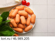 Тарелка вкусных отварных колбасок с шпинатом и помидорами на белом кафельном фоне. Стоковое фото, фотограф Pixel_shot / Фотобанк Лори