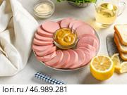 Тарелка с вкусной нарезанной отварной колбасой и соусом на светлом фоне. Стоковое фото, фотограф Pixel_shot / Фотобанк Лори