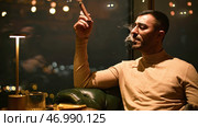 Man smokes cigar in luxury restaurant at night. Стоковое фото, фотограф David Kashakhi / Фотобанк Лори