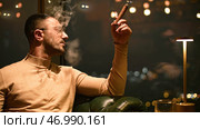 Man smokes cigar in luxury restaurant at night. Стоковое фото, фотограф David Kashakhi / Фотобанк Лори