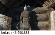 A medieval warrior in chain armor and a sword coming to wooden house. Стоковое фото, фотограф David Kashakhi / Фотобанк Лори