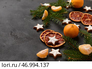 Звездообразное имбирное печенье с мандаринами, сушеным апельсином и ветвями ели на черном фоне. Стоковое фото, фотограф Pixel_shot / Фотобанк Лори