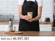 Женщина-бариста держит стакан с вкусным кофе на деревянном столе на кухне. Стоковое фото, фотограф Pixel_shot / Фотобанк Лори