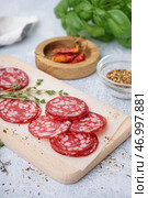 Деревянная доска с ломтями вкусной салями на светлом фоне. Стоковое фото, фотограф Pixel_shot / Фотобанк Лори