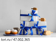 Подарки для празднования Хануки, вкусные пончики и крутильные вертящиеся стручки на светлом фоне. Стоковое фото, фотограф Pixel_shot / Фотобанк Лори