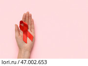 Женщина с красной лентой на розовом фоне. Концепция Всемирного дня борьбы со СПИДом. Стоковое фото, фотограф Pixel_shot / Фотобанк Лори