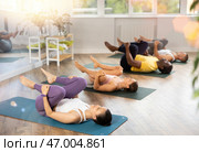 Asian woman performing Pawanmuktasana at group yoga session. Стоковое фото, фотограф Яков Филимонов / Фотобанк Лори