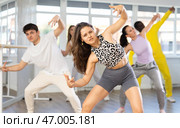 Positive active young woman dancing modern dance with other international people during group training. Стоковое фото, фотограф Яков Филимонов / Фотобанк Лори