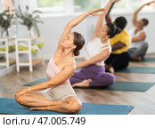 Fit girl practicing lotus pose with twist and side bend at yoga session. Стоковое фото, фотограф Яков Филимонов / Фотобанк Лори