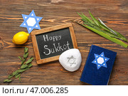 Четыре вида (лулав, хадас, арава, этрог), бумажная звезда Давида, кипа и меловая доска с надписью СЧАСТЛИВОГО СУККОТ на деревянном фоне. Стоковое фото, фотограф Pixel_shot / Фотобанк Лори