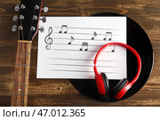 Нотный лист, современные наушники, виниловая пластинка и гитара на деревянном фоне. Стоковое фото, фотограф Pixel_shot / Фотобанк Лори