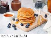 Деревянная доска с вкусными блинами с голубикой и кленовым сиропом на белом фоне. Стоковое фото, фотограф Pixel_shot / Фотобанк Лори