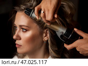 Hair Stylist Curling Beautiful Woman's Hair Indoors During a Professional Beauty Session. Стоковое фото, фотограф Aleksandr Golubev / Фотобанк Лори