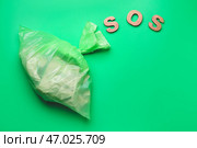 Мешок с мусором и словом SOS на цветном фоне. Концепция экологии. Стоковое фото, фотограф Pixel_shot / Фотобанк Лори