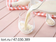 Переливание рисового молока из кувшина в стакан на столе. Стоковое фото, фотограф Pixel_shot / Фотобанк Лори