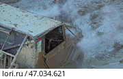 A muddy off-road vehicle is submerged in a deep puddle, creating a cloud of spray and casting a dark shadow. The vehicle's engine is running and steam is rising from the engine compartment. Стоковое фото, фотограф Воловодов Владимир / Фотобанк Лори