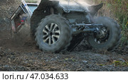 The off-road vehicle prepared for heavy off-roading struggles to overcome the muddy slope, its large tires kicking up thick mud. The SUV is tilted at a dangerous angle, with navigator visible in cab. Стоковое фото, фотограф Воловодов Владимир / Фотобанк Лори