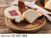 Деревянная доска с ассортиментом вкусных сыров на столе. Стоковое фото, фотограф Pixel_shot / Фотобанк Лори