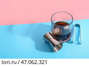 Стакан рома с кубиками льда, щипцами и мерной чашкой на ярком фоне. Стоковое фото, фотограф Pixel_shot / Фотобанк Лори