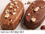 Вкусное мороженое, покрытое шоколадом и измельченными орехами на белом столе, крупный план. Стоковое фото, фотограф Pixel_shot / Фотобанк Лори