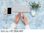 Женщина наносит антисептик на руки за синим столом в офисе. Стоковое фото, фотограф Pixel_shot / Фотобанк Лори