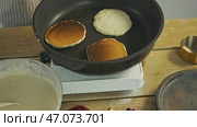 The cook turns over the pancakes on the griddle, which are burnt due to a lack of oil. high angle. Стоковое видео, видеограф Strunov David / Фотобанк Лори