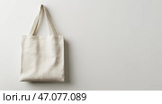 Simple cream-colored tote bag hanging against a light gray wall, copy space. Простая сумка-тоут кремового цвета на фоне светло-серой стены, копия. Стоковое AI-изображение, AI-художник Katsiaryna Repich / Фотобанк Лори