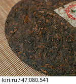 CloseUp of a Compressed Puerh Tea Cake on a Bamboo Mat, showcasing its rich history and character. Стоковое фото, фотограф David Kashakhi / Фотобанк Лори