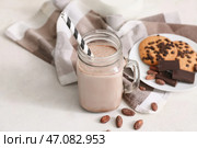 Банка с крышкой, наполненная сладким шоколадным молоком, с вкусным печеньем и какао-бобами на белом фоне. Стоковое фото, фотограф Pixel_shot / Фотобанк Лори