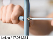 Мужчина-рабочий затягивает винт в металлической раме с помощью отвертки, крупным планом. Стоковое фото, фотограф Pixel_shot / Фотобанк Лори
