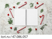 Блокнот с рождественскими шарами, ветками кипариса и игрушками в виде леденцовой трости на белом грубом фоне. Стоковое фото, фотограф Pixel_shot / Фотобанк Лори