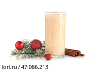 Стакан вкусного коктейля яичного гоголя-моголя с корицей, еловыми ветками и рождественскими шарами на белом фоне. Стоковое фото, фотограф Pixel_shot / Фотобанк Лори
