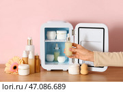 Женские руки достают сыворотку из маленького косметического холодильника на столе на розовом фоне. Крупный план. Стоковое фото, фотограф Pixel_shot / Фотобанк Лори