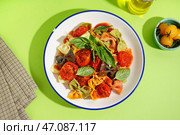 Миска вкусной пасты фарфалле с томатами и базиликом на зеленом фоне. Стоковое фото, фотограф Pixel_shot / Фотобанк Лори