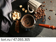 Джезва с горячим сваренным кофе, зерна, чашка и сахар на черном фоне. Стоковое фото, фотограф Pixel_shot / Фотобанк Лори