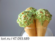 Вафельные рожки с вкусным фисташковым мороженым на сером фоне, близком расстоянии. Стоковое фото, фотограф Pixel_shot / Фотобанк Лори