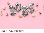 Цифра 2025 из фольгированных шаров и рождественских украшений на розовом фоне. Стоковое фото, фотограф Pixel_shot / Фотобанк Лори