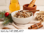 Миска с традиционным украинским кутьей, ветка рождественской елки и кувшин с узваром на белом столе. Стоковое фото, фотограф Pixel_shot / Фотобанк Лори