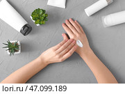 Молодая женщина, применяя крем для рук за столом. Стоковое фото, фотограф Pixel_shot / Фотобанк Лори