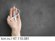 Мужская рука держа голубую ленту на серой предпосылке. Концепция рака простаты. Стоковое фото, фотограф Pixel_shot / Фотобанк Лори