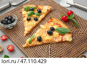 Ломтики вкусной итальянской пиццы с оливками на плетеной циновке. Стоковое фото, фотограф Pixel_shot / Фотобанк Лори