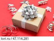 Подарочная коробка с бантом и серпантином на красном фоне крупным планом. Стоковое фото, фотограф Pixel_shot / Фотобанк Лори